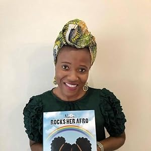 Photo of Lorreta Chindo-Besong smiling and holding up a copy of her book, Nain Rocks Her Afro